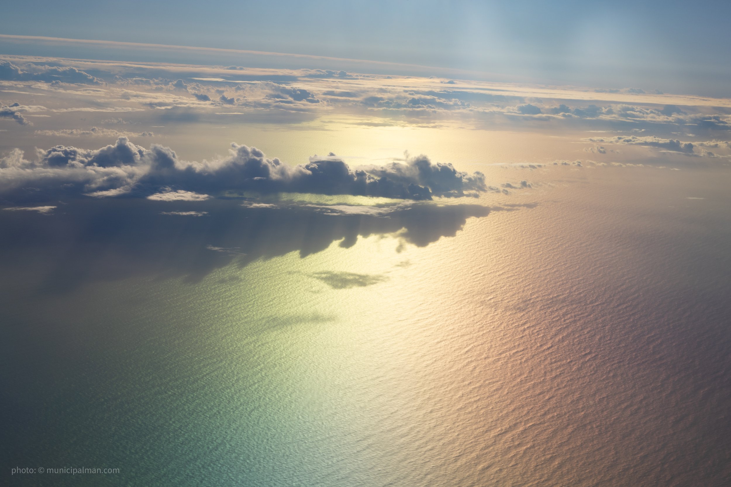 Sunlight reflecting off the ocean with scattered clouds overhead