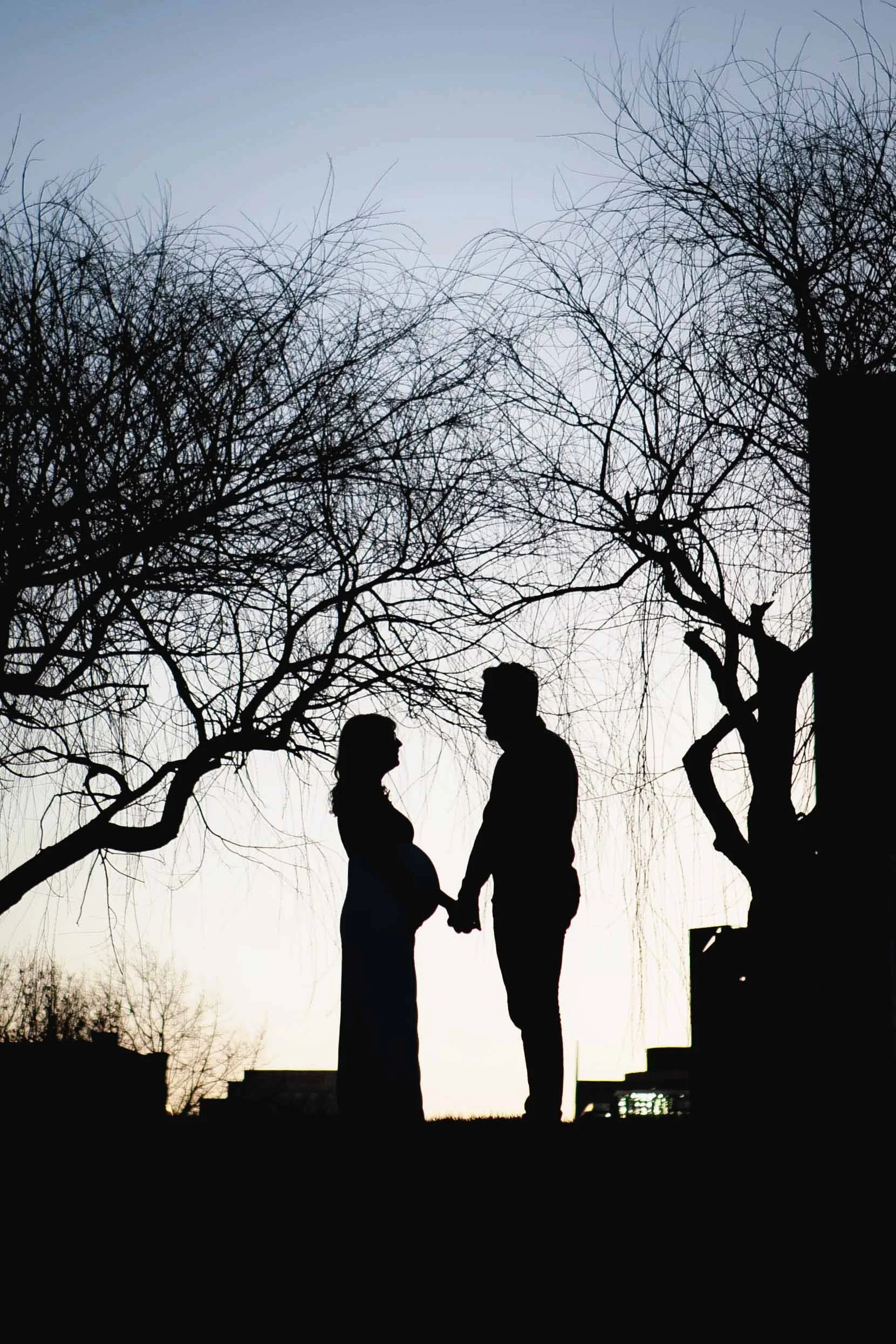 Maternity photo of a couple silhouetted at the White River Canal downtown Indianapolis facing each other