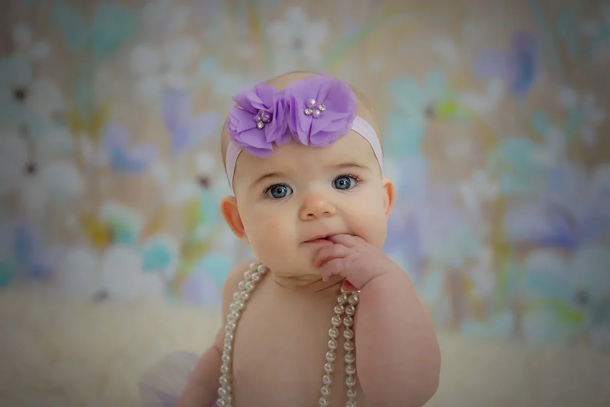 Six month baby milestone portrait featuring a baby wearing a purple headband and pearls, photographed in Indianapolis