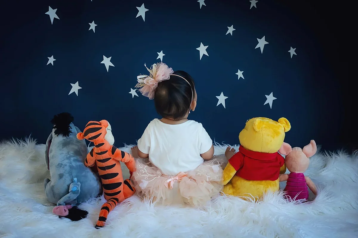 One-year-old baby girl in a white dress and headband, smiling during a milestone photography session in Indianapolis.