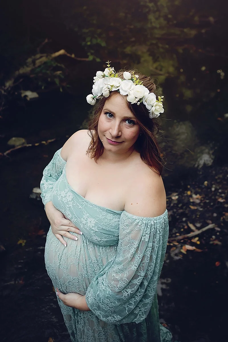 Expectant mother wearing a soft sage green lace gown and floral crown during an outdoor maternity photography session in Indianapolis