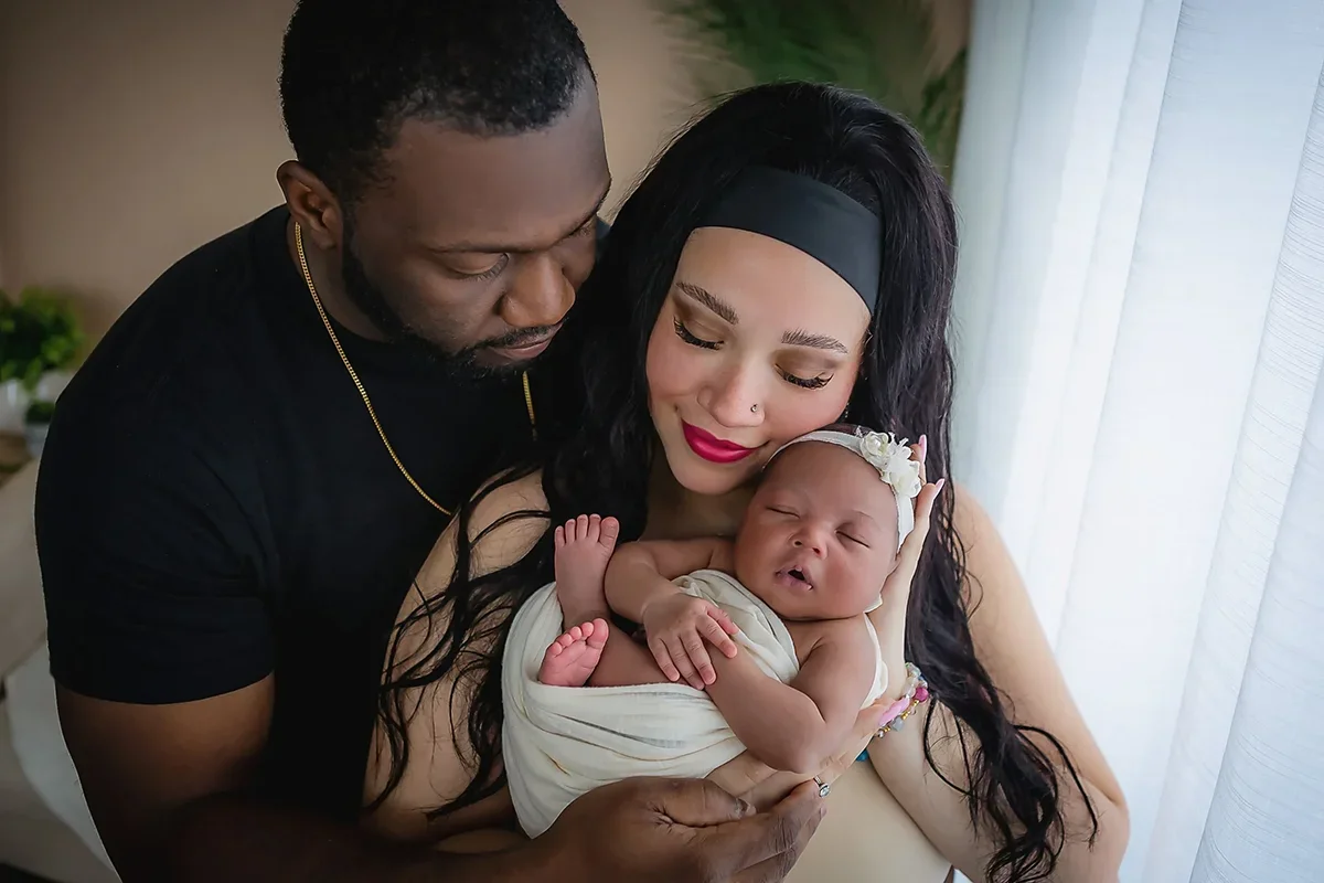 Newborn baby girl held safely in mom and dad's arms.