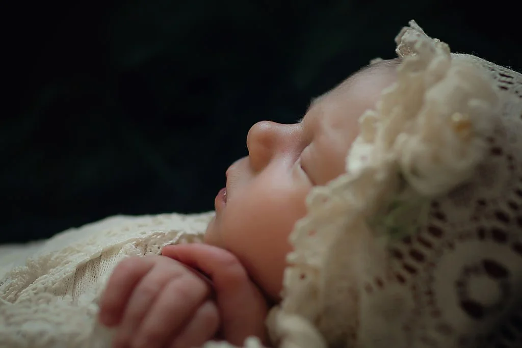 Close up of newborn baby girl showing her tiny hands and sweet face during a newborn photography session at Memory Lane Photography.