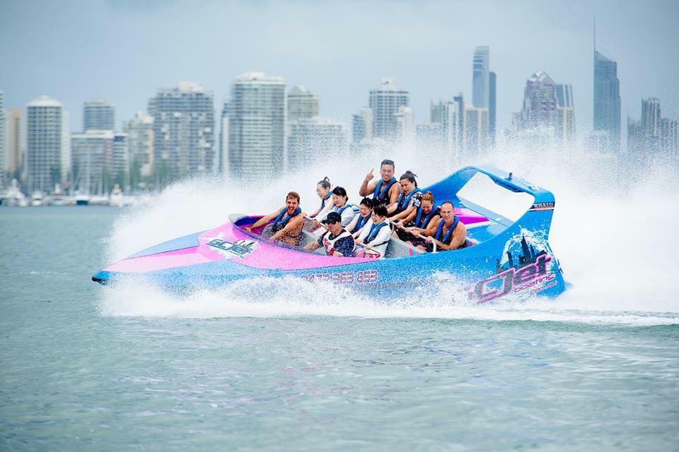 10 people on a high-speed jet boat, speeding through the water with the Gold Coast skyline in the background