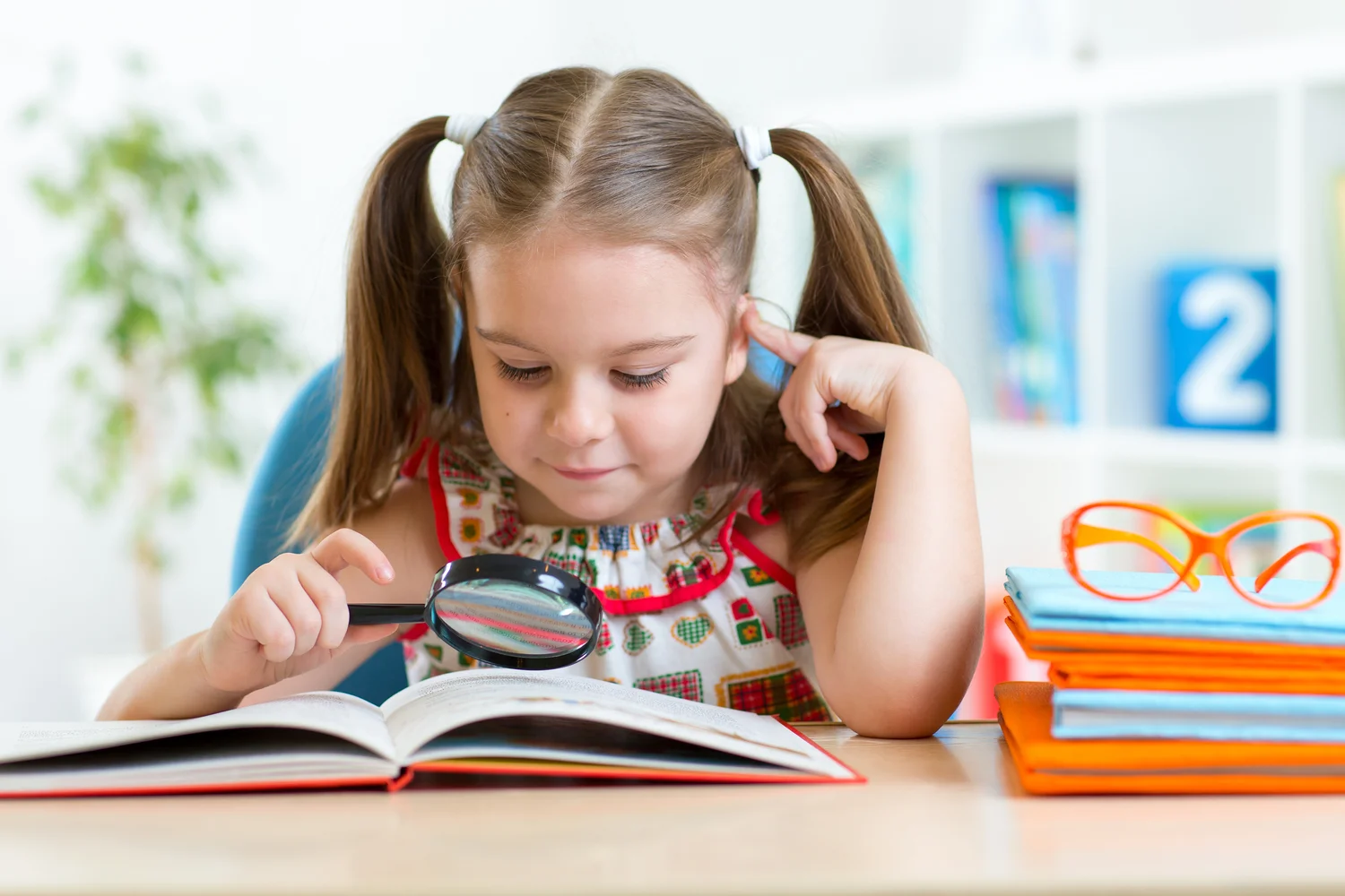 Young girl using a magnifying glass to find clues in a book