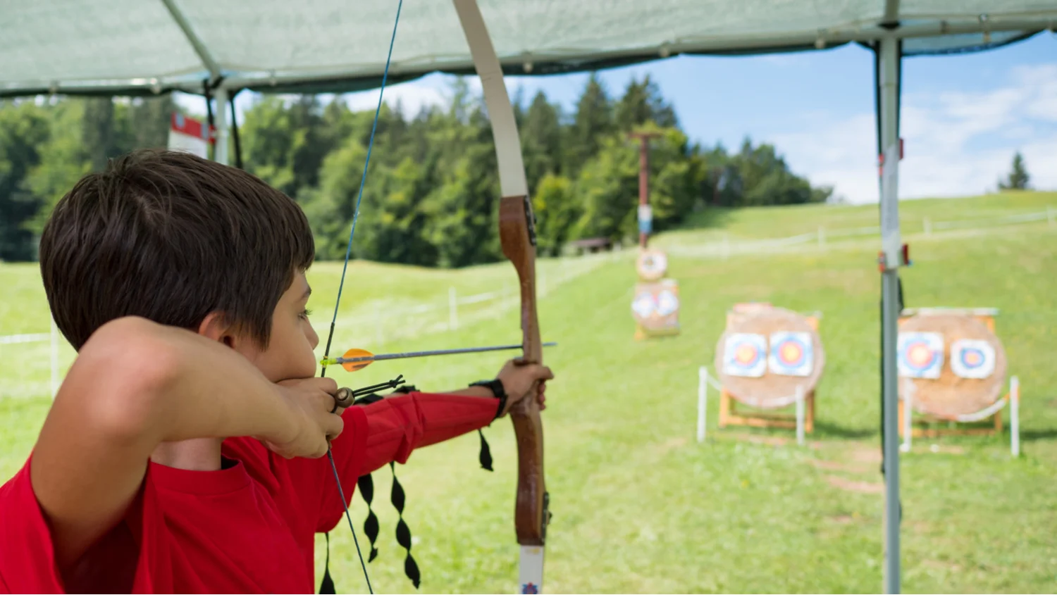 A young boy preparing to shoot a target with a bow and arrow