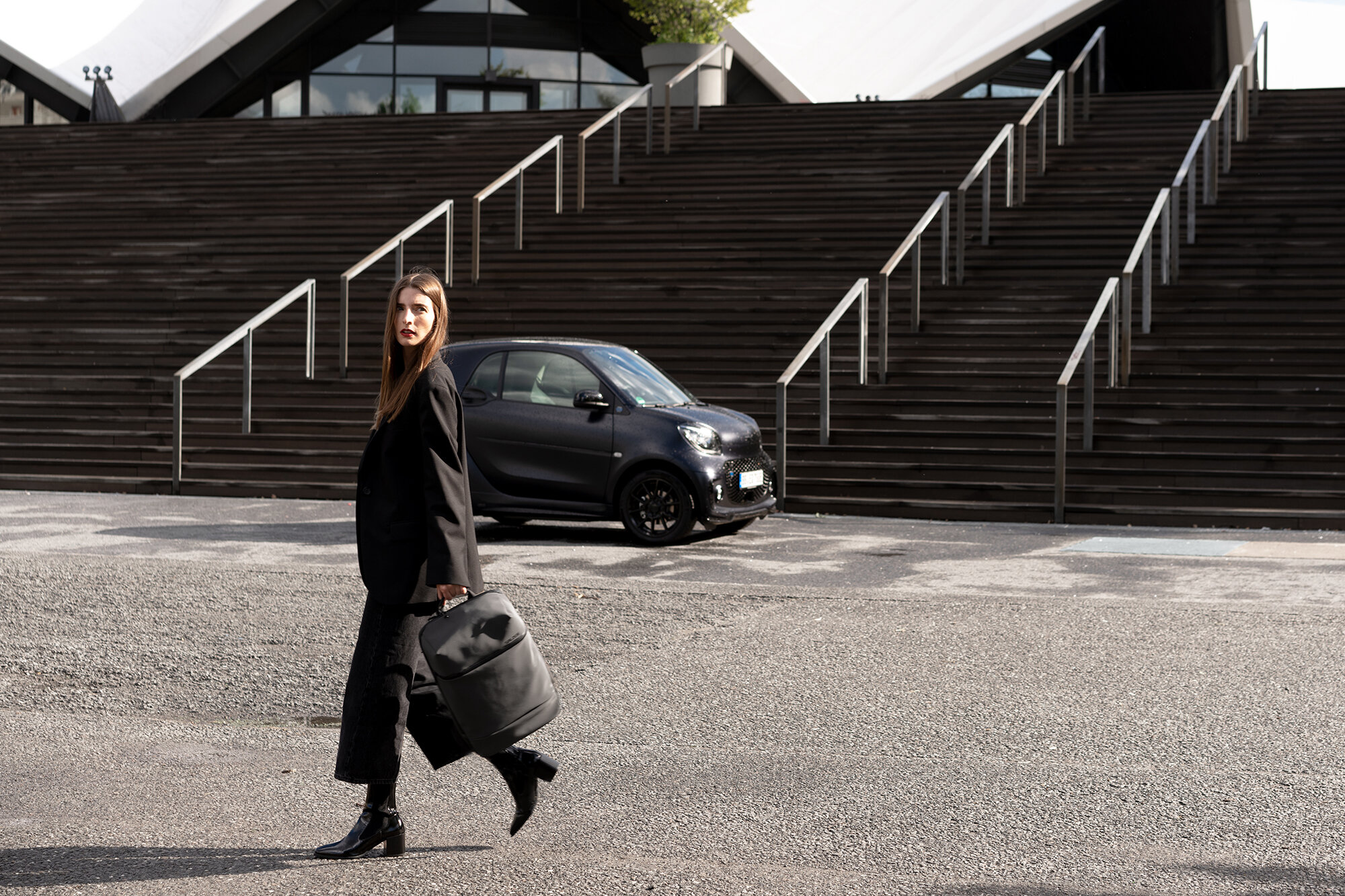 Britta Reineke carrying the SALZEN backpack in front of the smart EQ fortwo