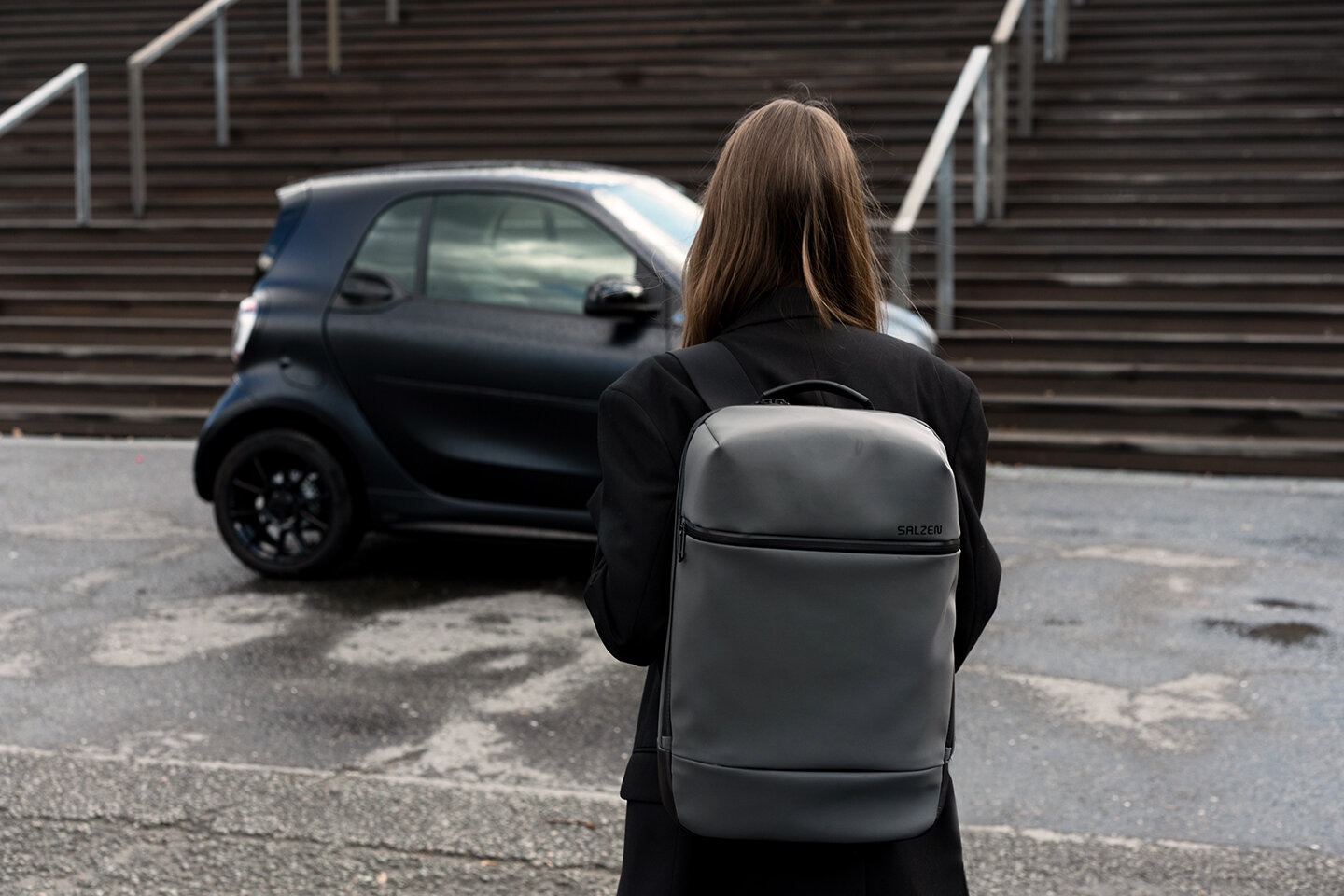 Britta Reineke wearing the SALZEN backpack in front of the smart EQ fortwo in bluedawn