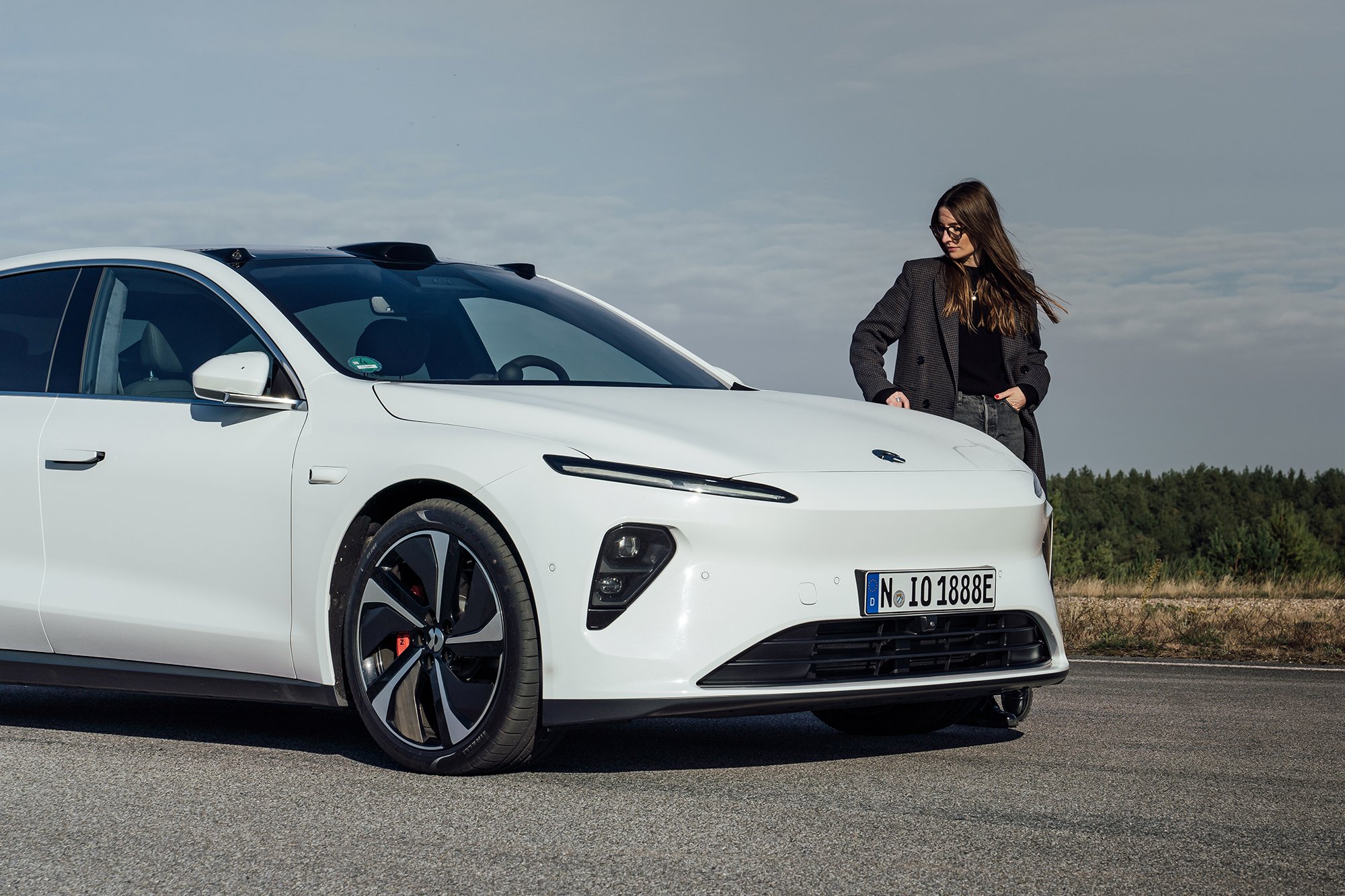 Britta Reineke, founder of ellectric stands next to the front of the all-electric white NIO ET7