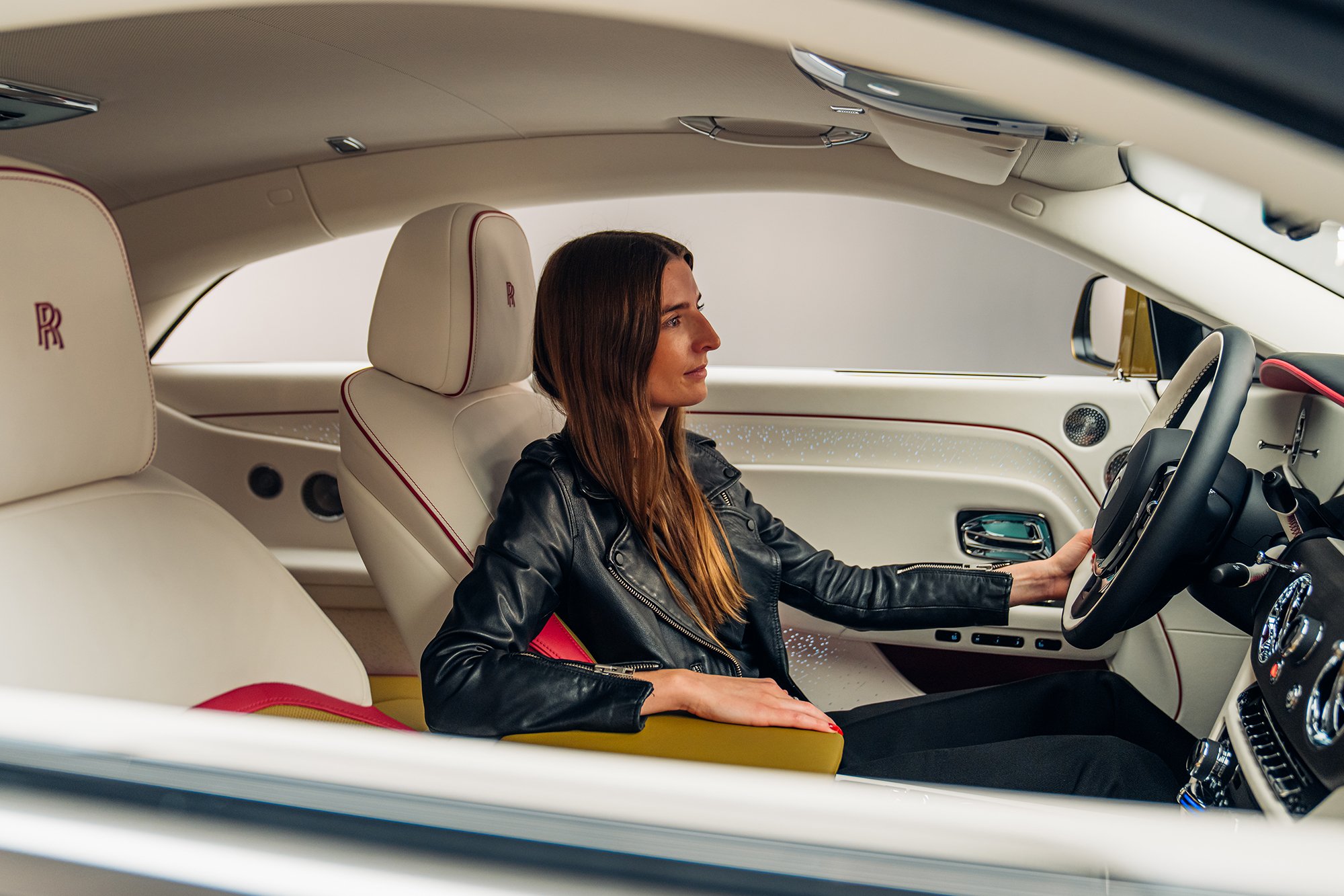 Britta Reineke, founder of ellectric sits behind the steering wheel of the first all-electric Rolls-Royce Spectre showcasing the luxurious interior design