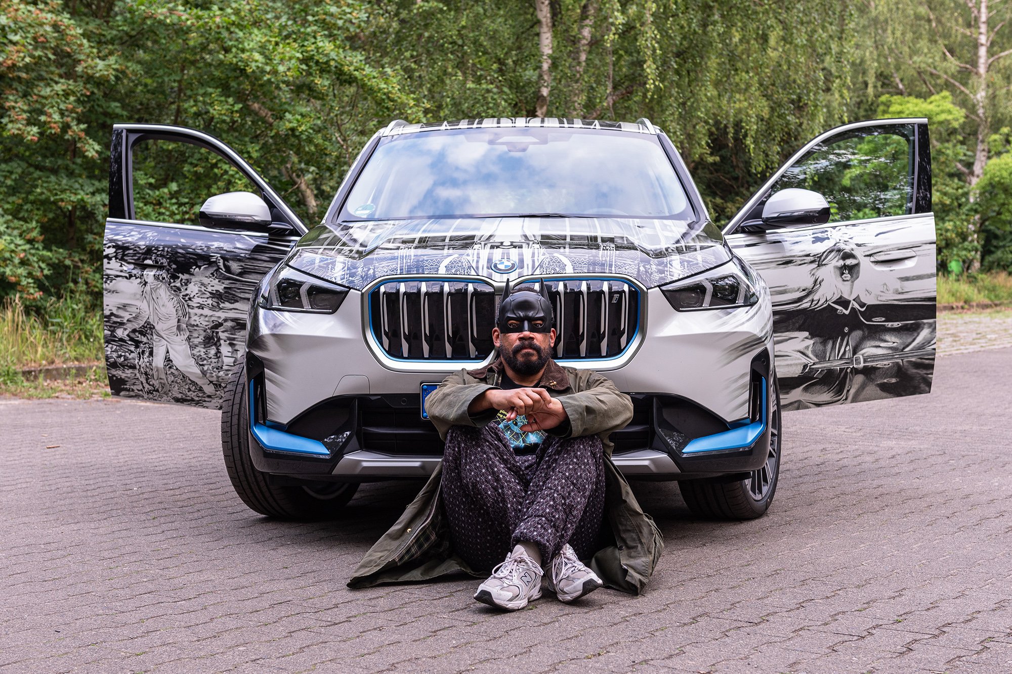 Artist MArc Brandenburg sitting infront of the BMW iX1 