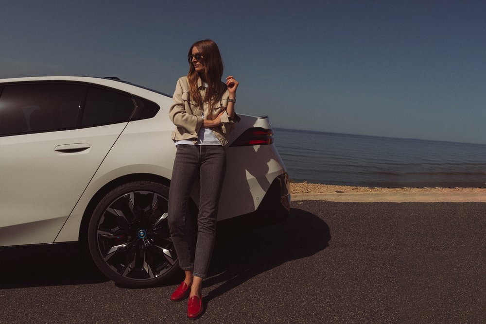 Britta Reineke, founder of ellectric leaning against the rear design of the all-electric BMW i5 M60