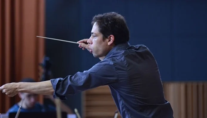 Conductor leading an orchestra with a baton in hand