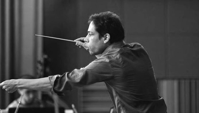 Conductor leading an orchestra with a baton in hand