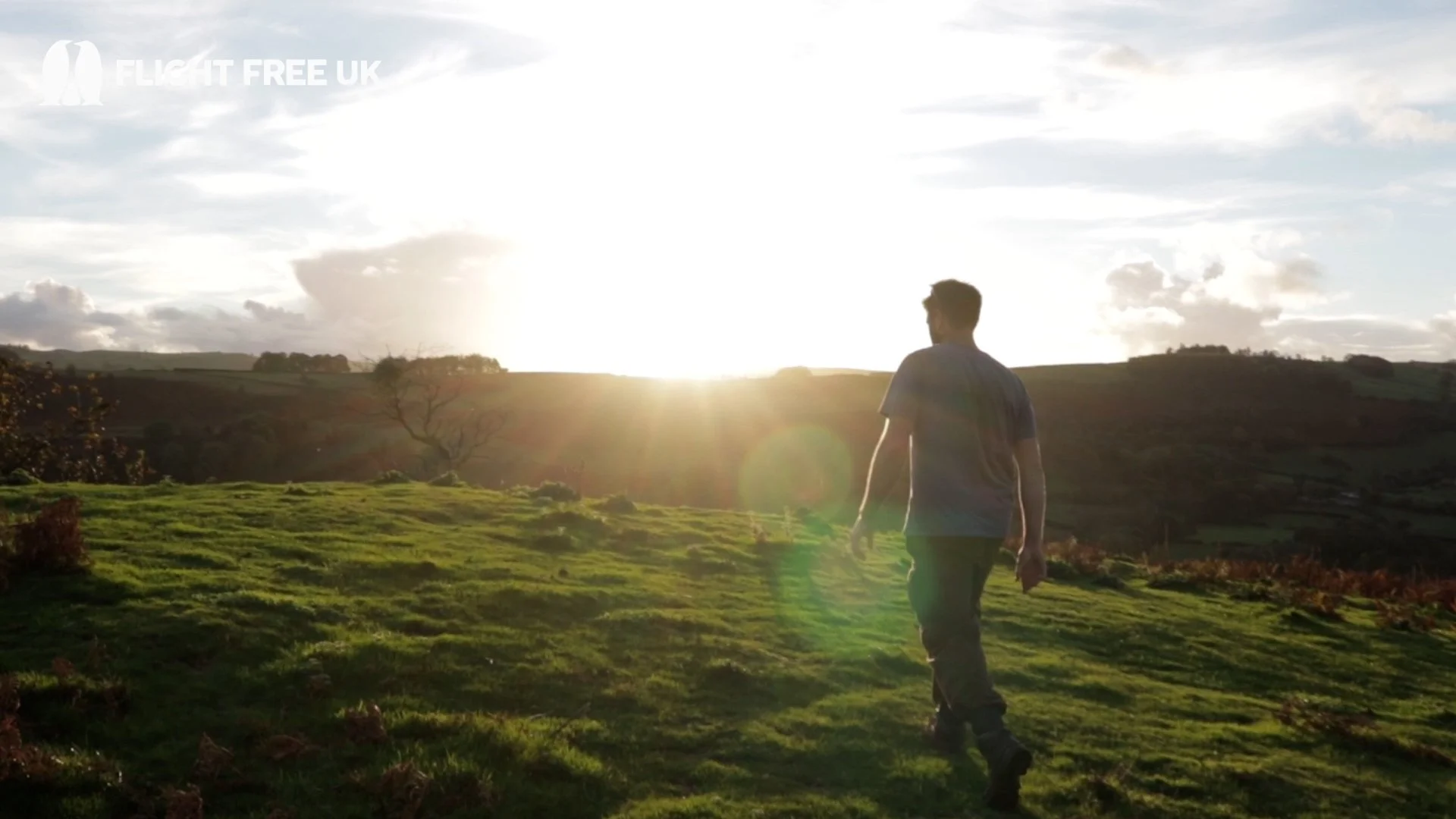 Mike walking over top a hill as the sunset beams down in front of him