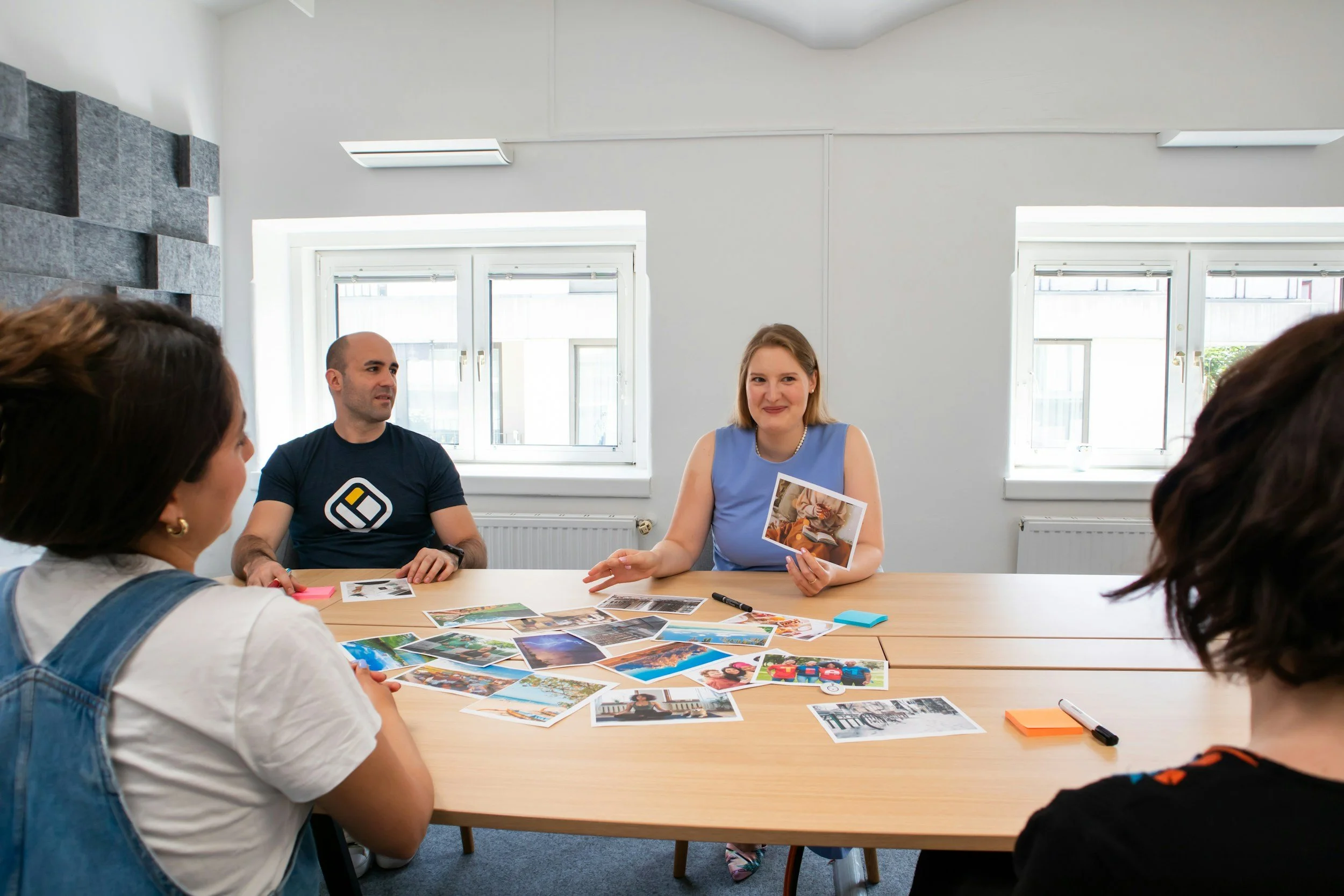 Groupe de personnes assises autour d'une table en réunion, discutant, avec des photos et des notes sur la table.