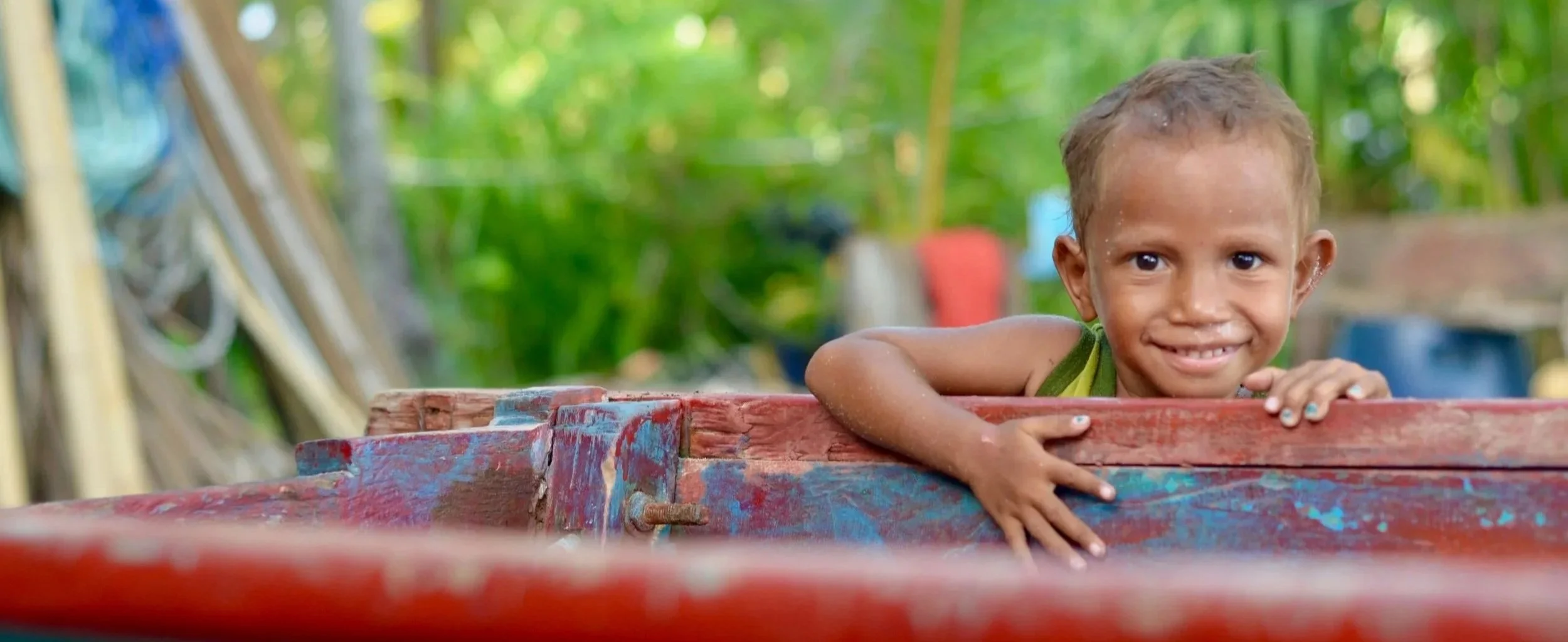 A child leaning over a hand-painted boat, representing joyful outcomes of thoughtful philanthropy