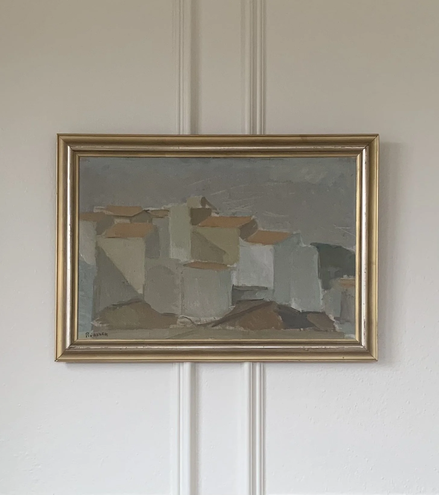 ‘Spanish Village in Summer’ (ca. 1960s), a framed oil painting showing a peaceful village cityscape of block-shaped buildings with tile roofs.