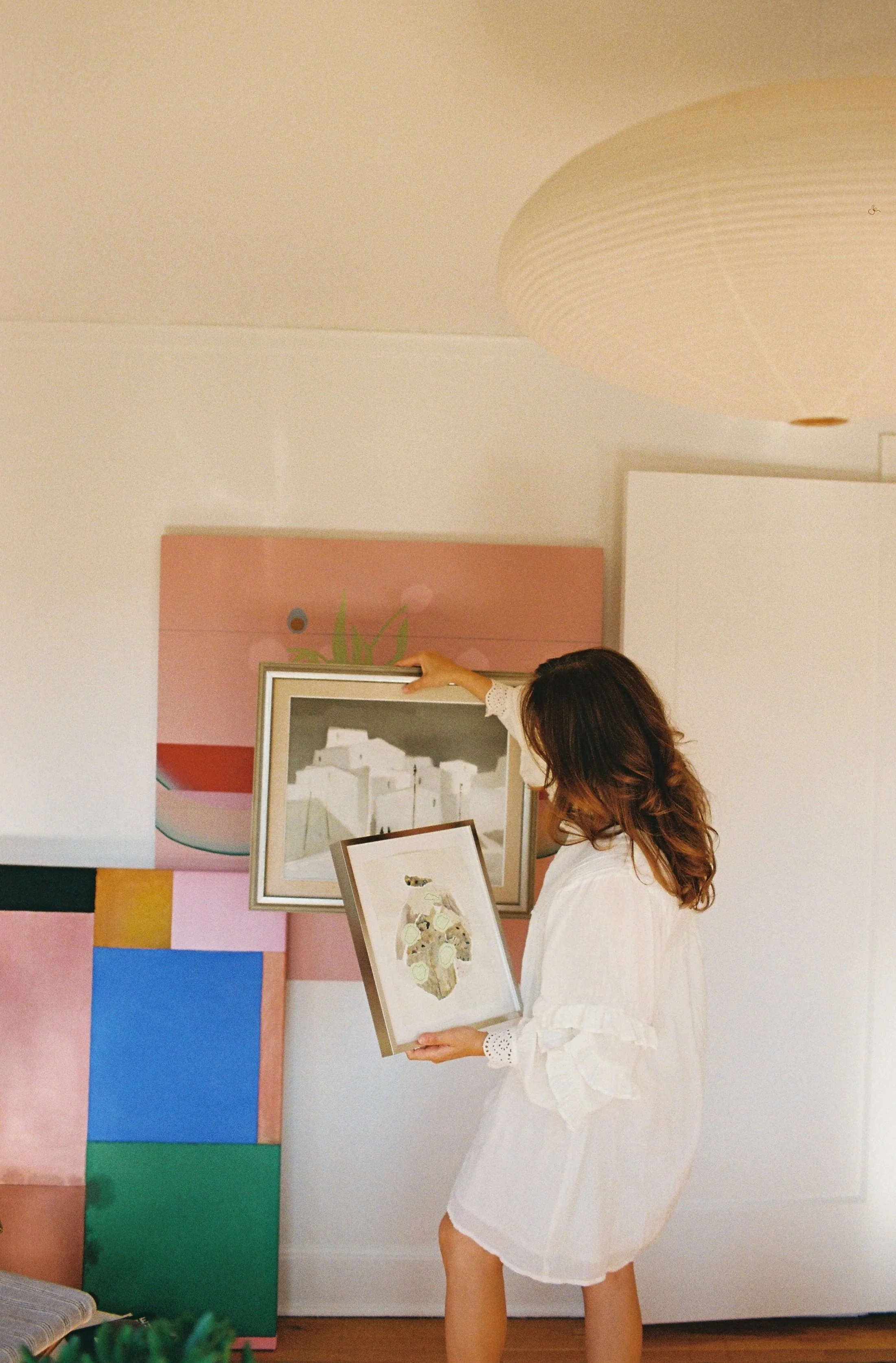 Woman arranging paintings and artworks in a bright studio space