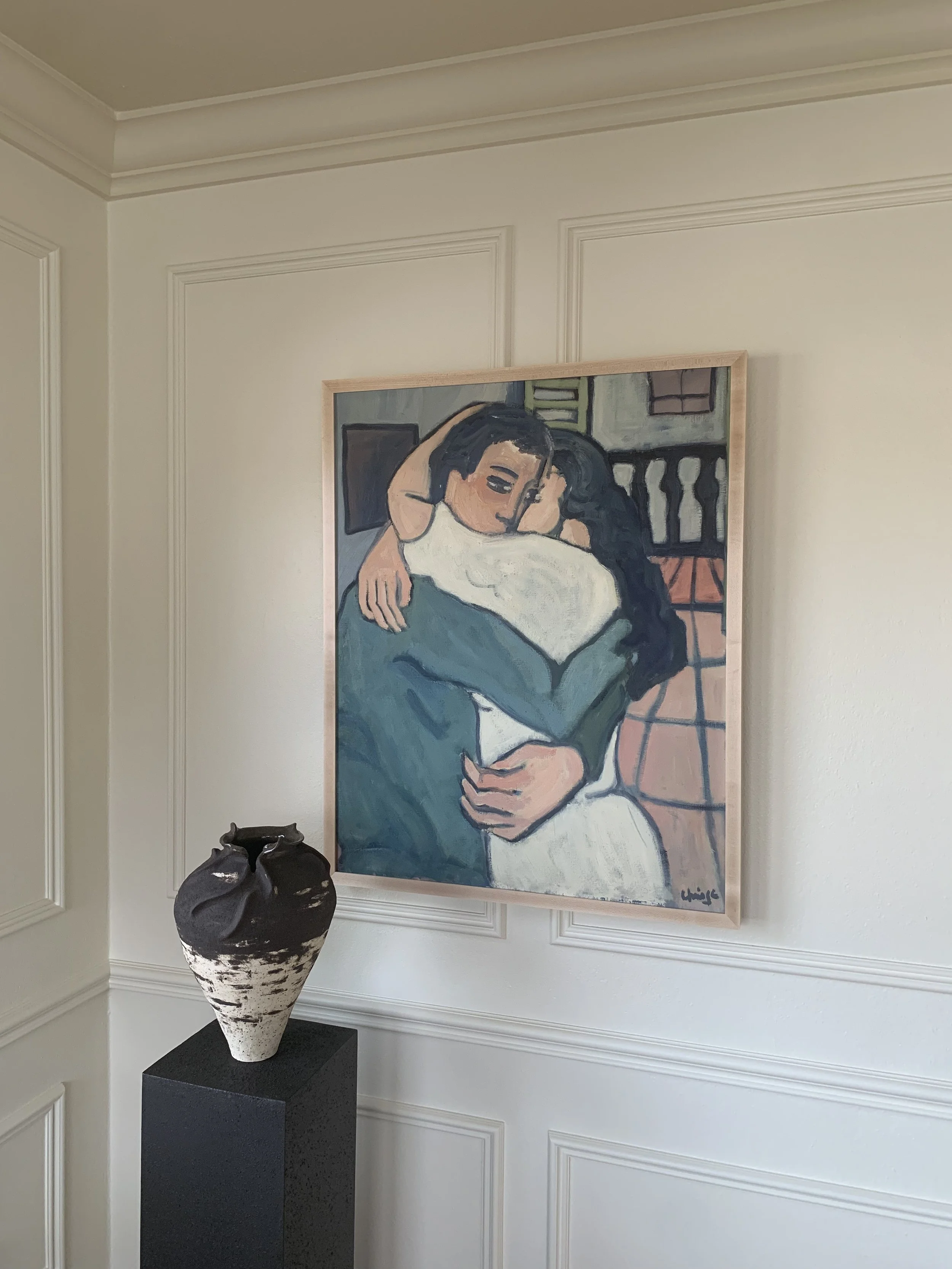 Detail of ‘Lovers Embrace’ (ca. 1960s), a framed oil painting showing the painting hung on a wall in a room.