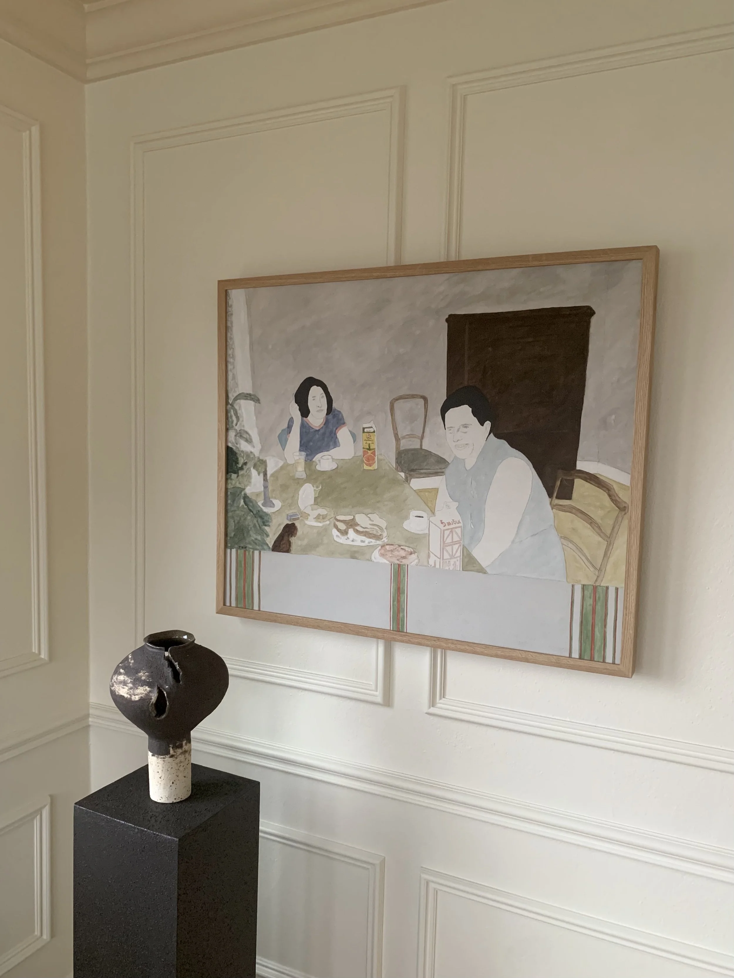 Detail of 'Breakfast' (ca. 1970s) by Rolf Pettersson showing the oil painting hanging on a wall in a room.