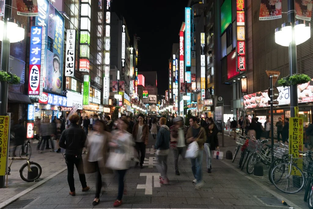 People spilling out from all corners on the busy streets of Tokyo against the myriad of neon lights.