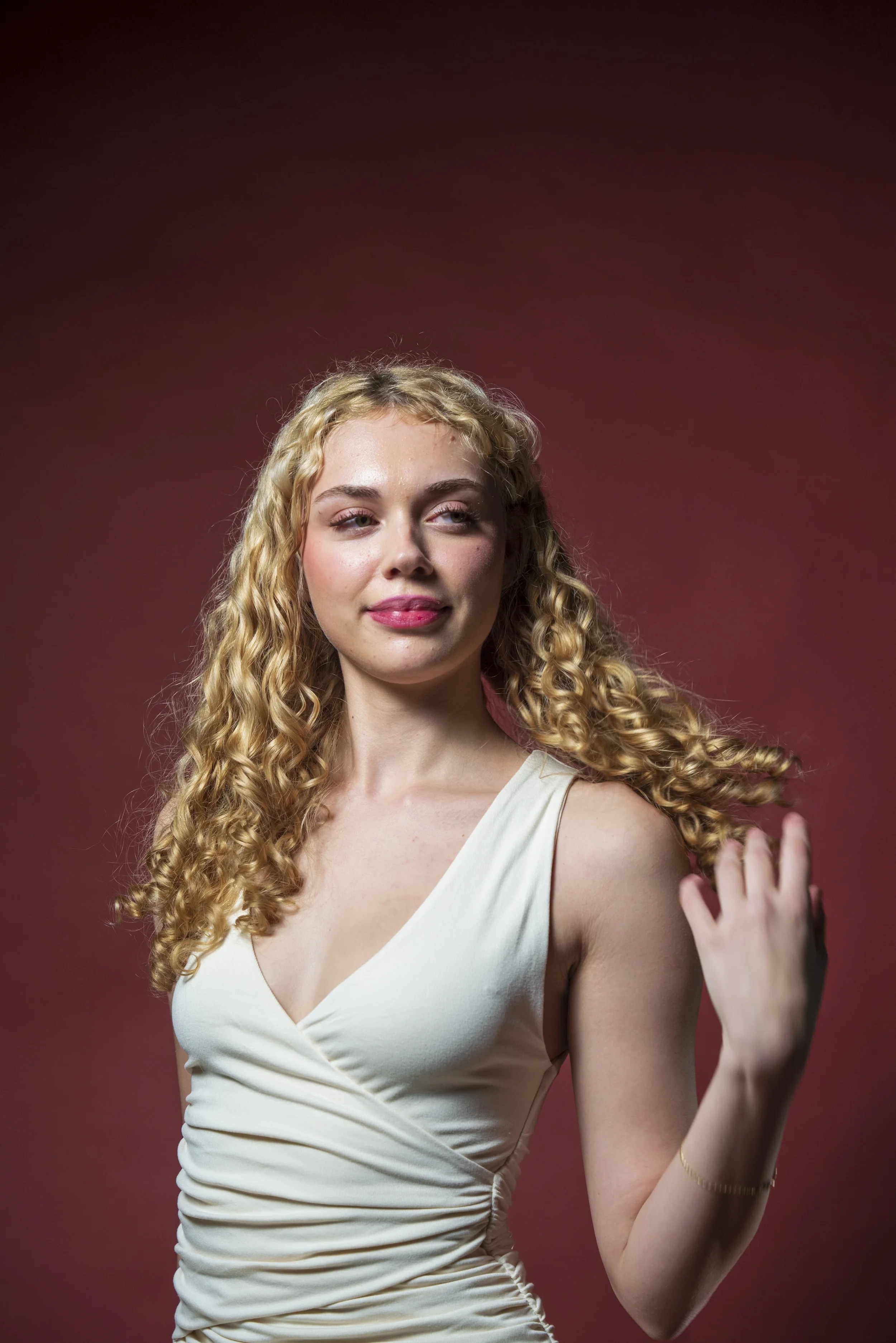 Model practising upper-body posture and controlled movement in a white dress during a studio photoshoot.