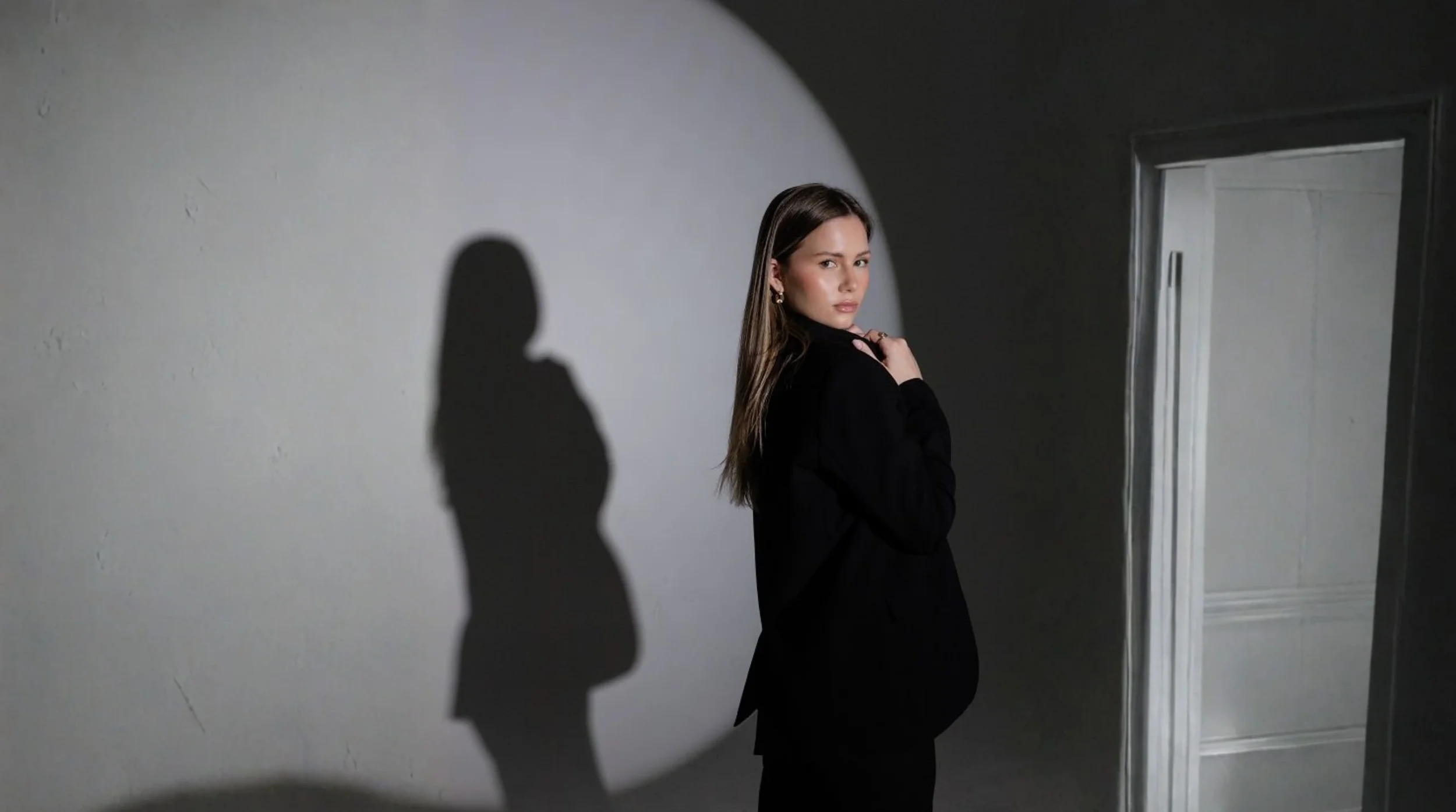 Aspiring fashion model in a professional black suit demonstrating agency-ready presentation during a studio photoshoot.