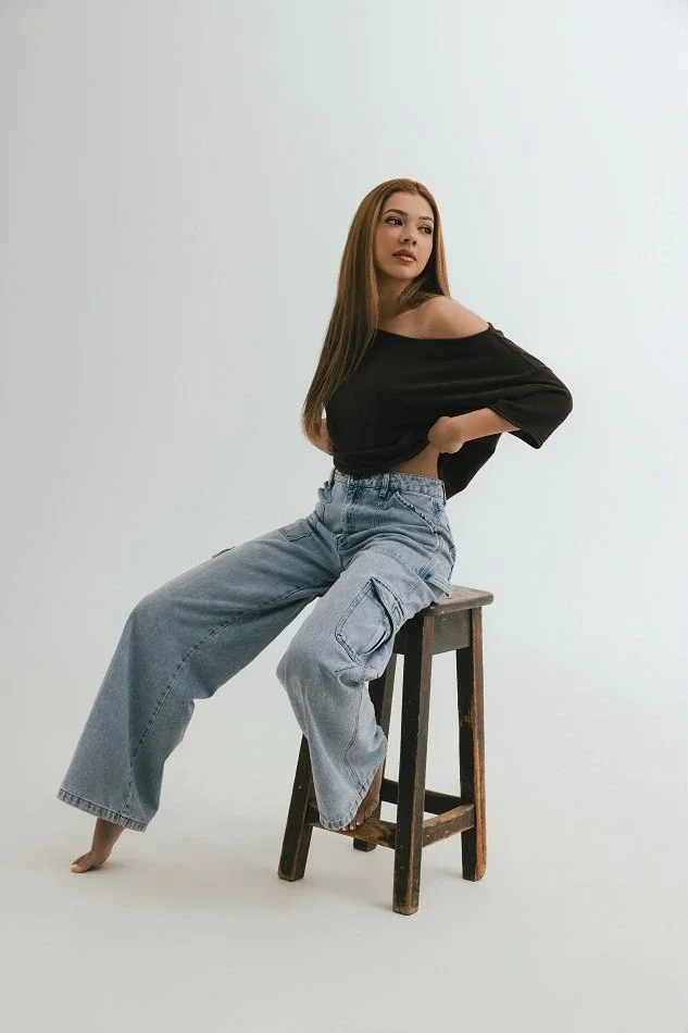 Beginner model practising posing on a stool in a simple home studio setup, building confidence and body awareness through independent modelling practice.
