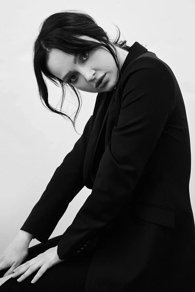 Model displaying an intense and emotive facial expression while posing in a black blazer, highlighting the importance of expression in fashion photography.