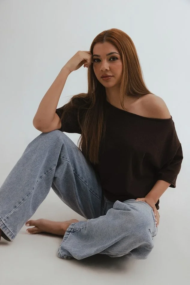 Aspiring model practising a relaxed seated pose on the floor at home, demonstrating self-training techniques for improving modelling skills without a photographer.