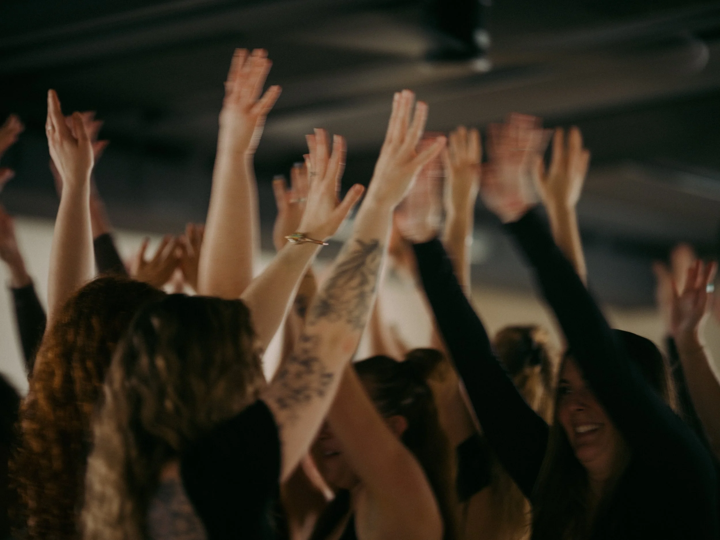 A crowd of people raising their hands in the air during a lively event or concert.
