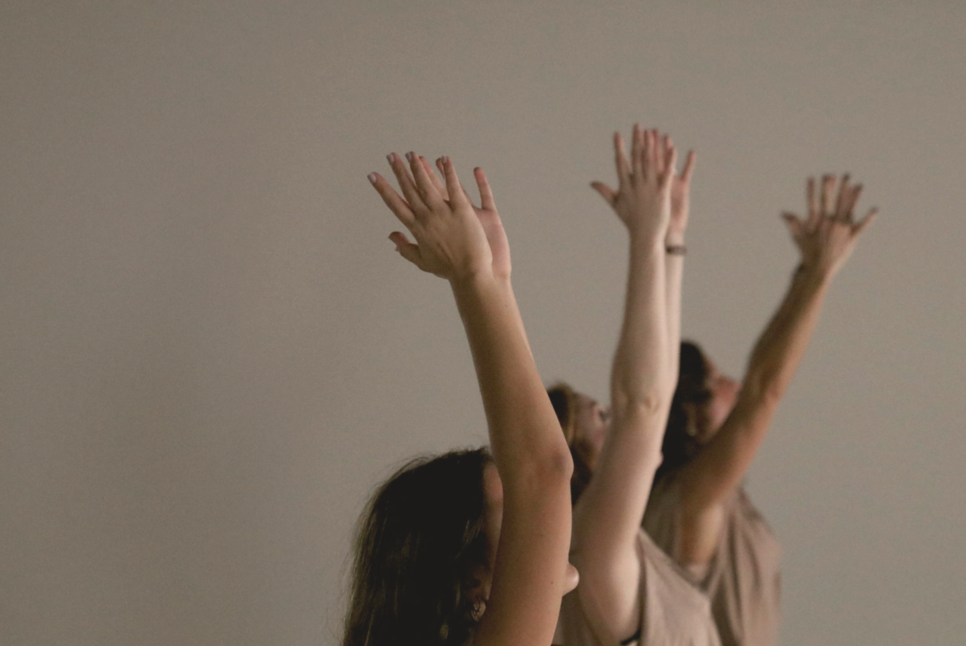 A group of people raising their hands in the air during a dance or exercise class.