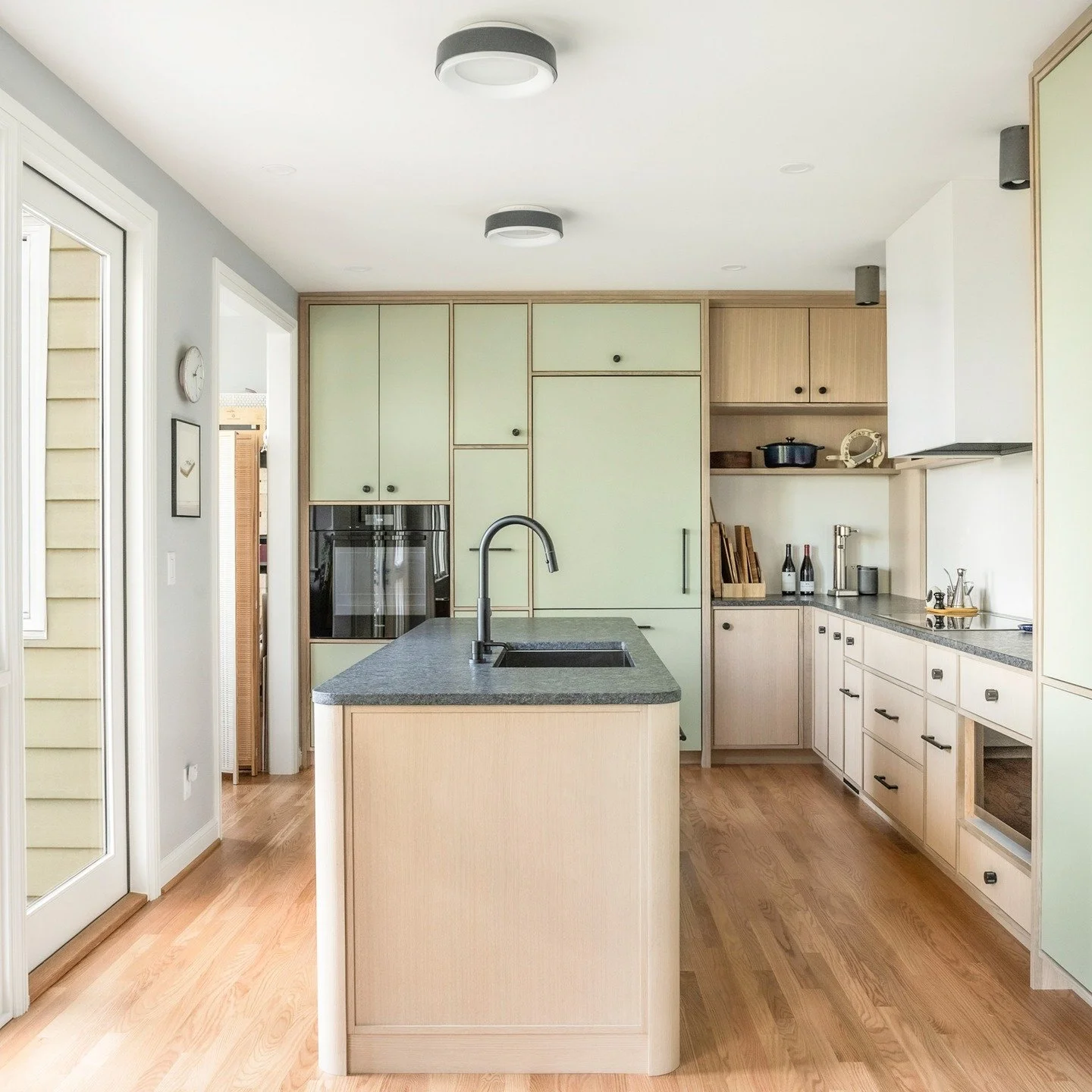This kitchen renovation creates a more inviting, entertainment-ready space by widening the opening to the dining room and expanding into the former garage. New windows and doors throughout bring in natural light and strengthen the connection between 