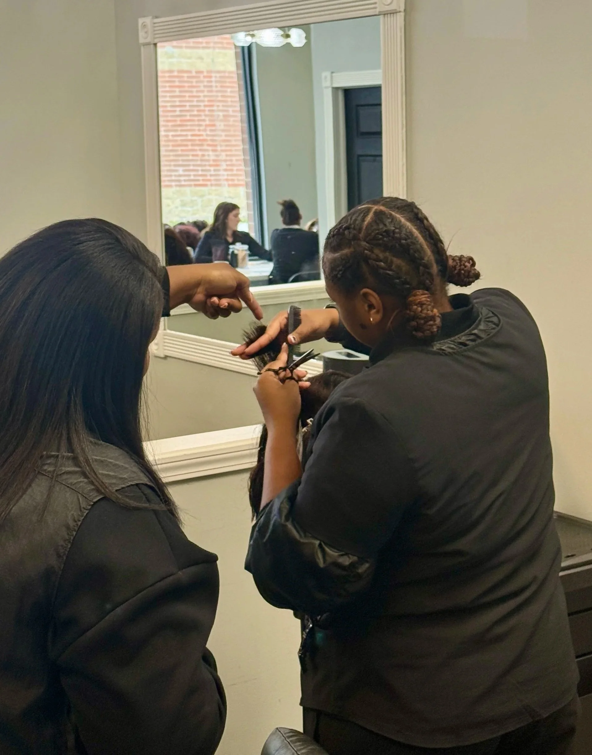 Cosmetology student receiving hands-on instruction while practicing precision cutting techniques in a salon classroom at Beautiful Luxe School of Cosmetology
