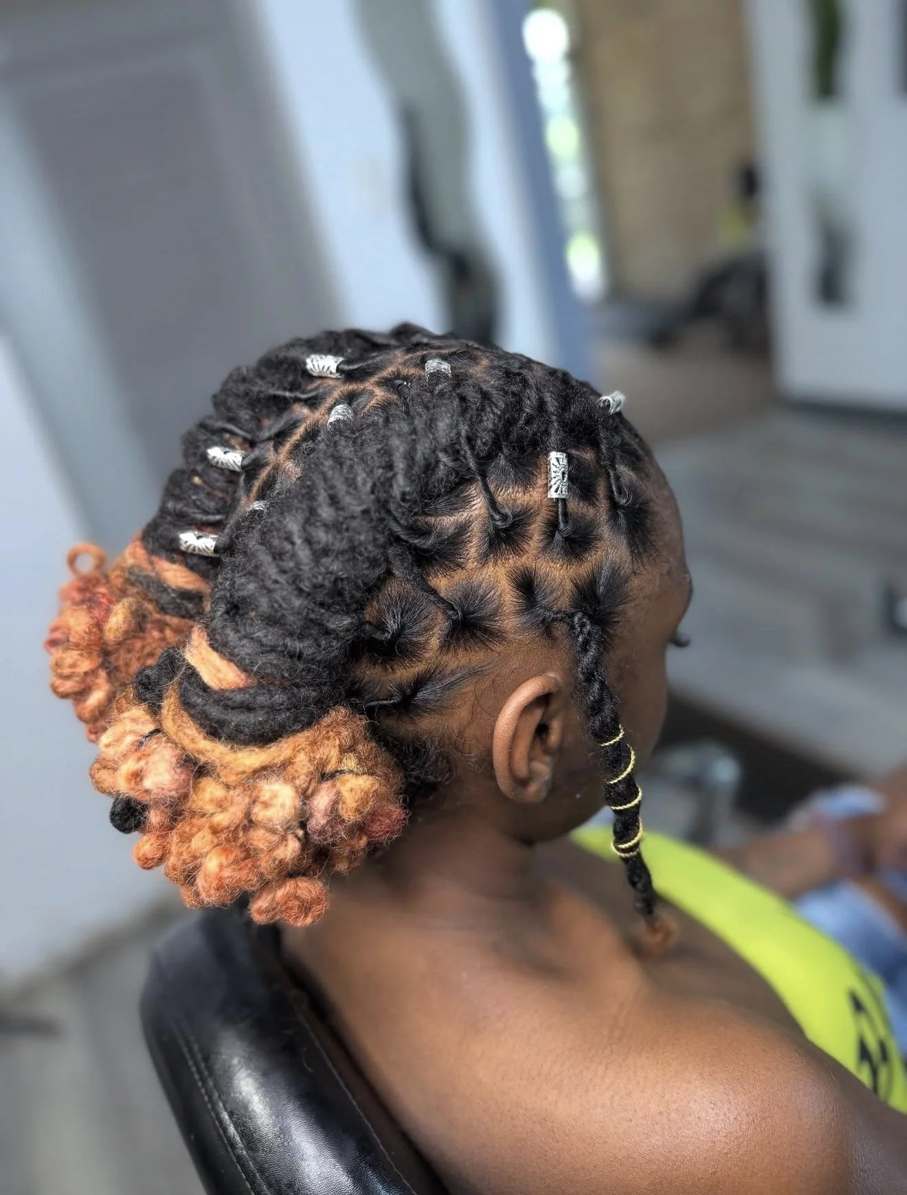 Protective loc style with copper-toned ends and decorative accents completed by Mekhiah The Loc Barber