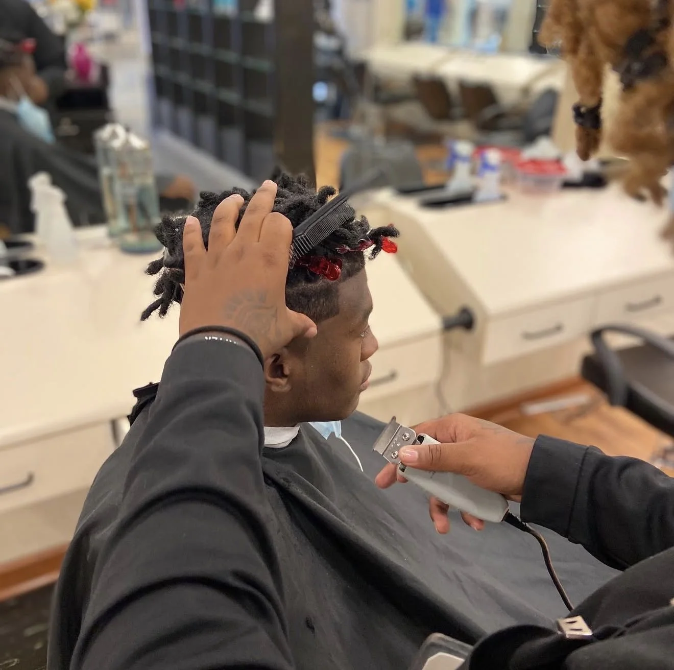 Cosmetology student performing clipper cutting and barbering technique on a client during hands-on training at Beautiful Luxe School of Cosmetology