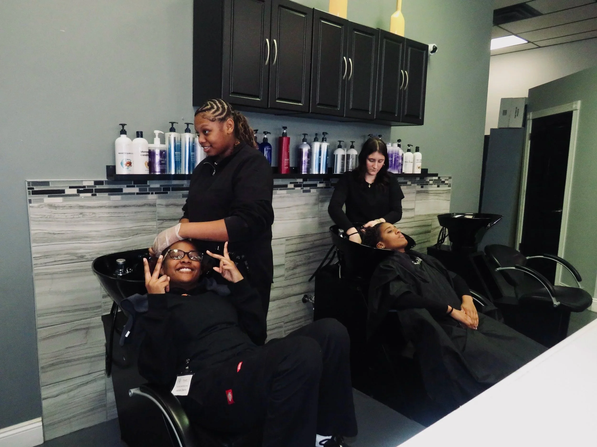 CTE Cosmetology students at Beautiful Luxe School of Cosmetology practicing shampoo and scalp treatments in a modern salon classroom