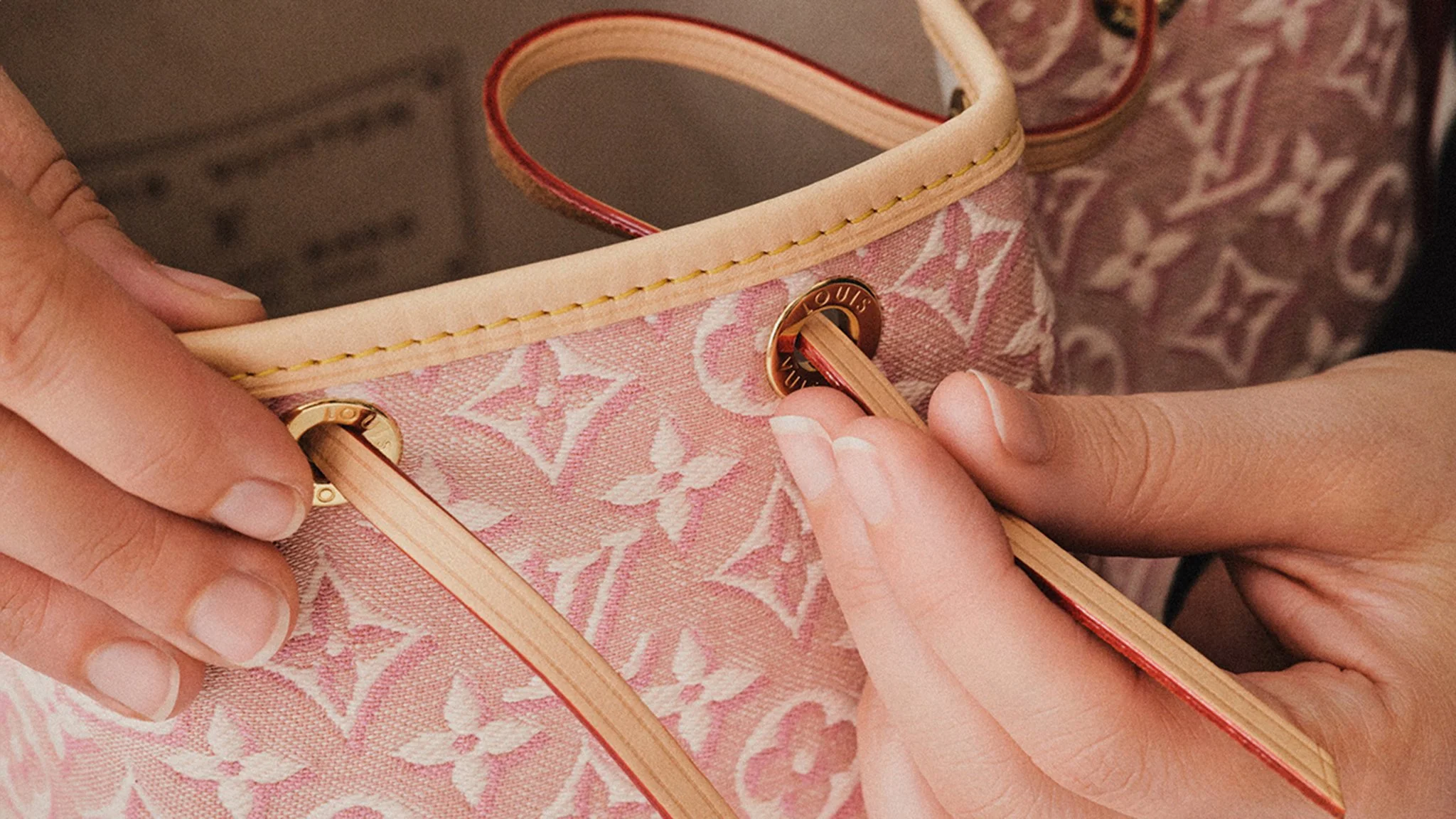 Inserting the loop through the eyelets of the Noe Monogram Embleme.jpg