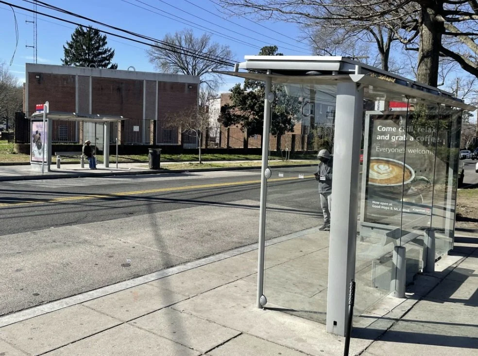 Road with glass-enclosed bus shelters on both sides of the street.