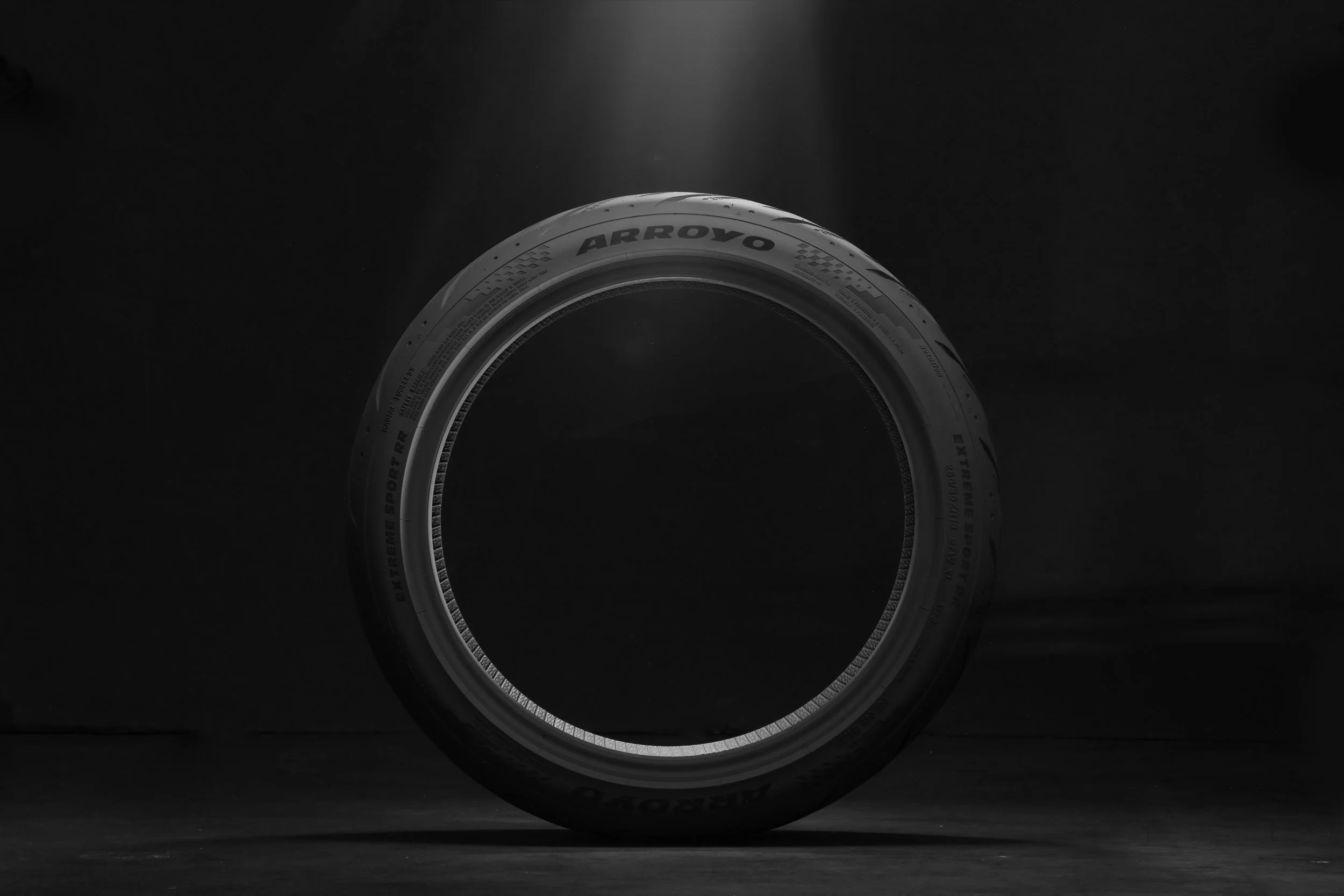 Arroyo Extreme Sport RR tire standing in a single spotlight on black, dramatic tire hero photography