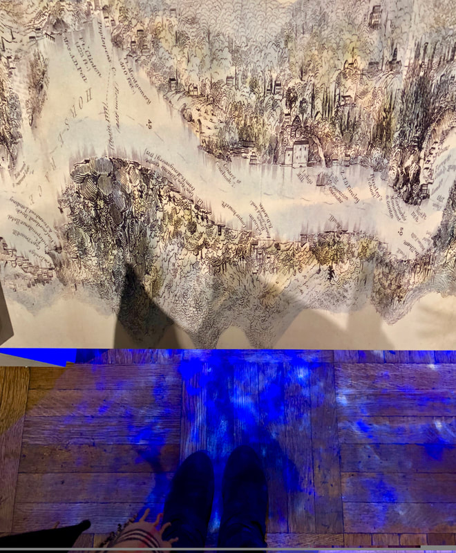 Water shadows play on the floor, under a panoramic map of the Hudson shoreline in Journeys Upriver. The effect of dappled sunlight through trees envelopes the visitor in The Adirondacks section.