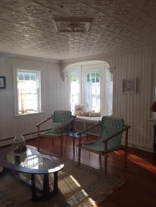 The living room on a sunny August morning. Note the intricately patterned tin ceiling and walls, as well as the picture window.