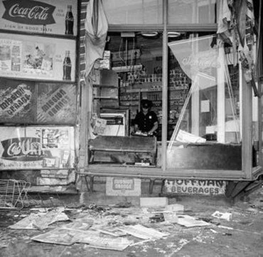 A police officer surveys damage in a looted Bed-Stuy store