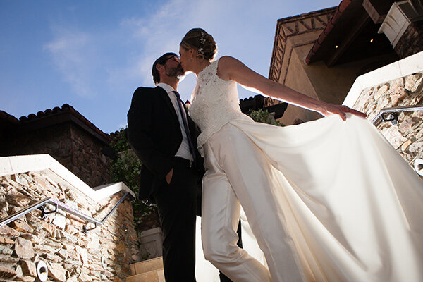 Groom-and-Bride-kissing-in-custom-made-white-bridal-suits-with-maxi-skirt-around-the-waist.jpg