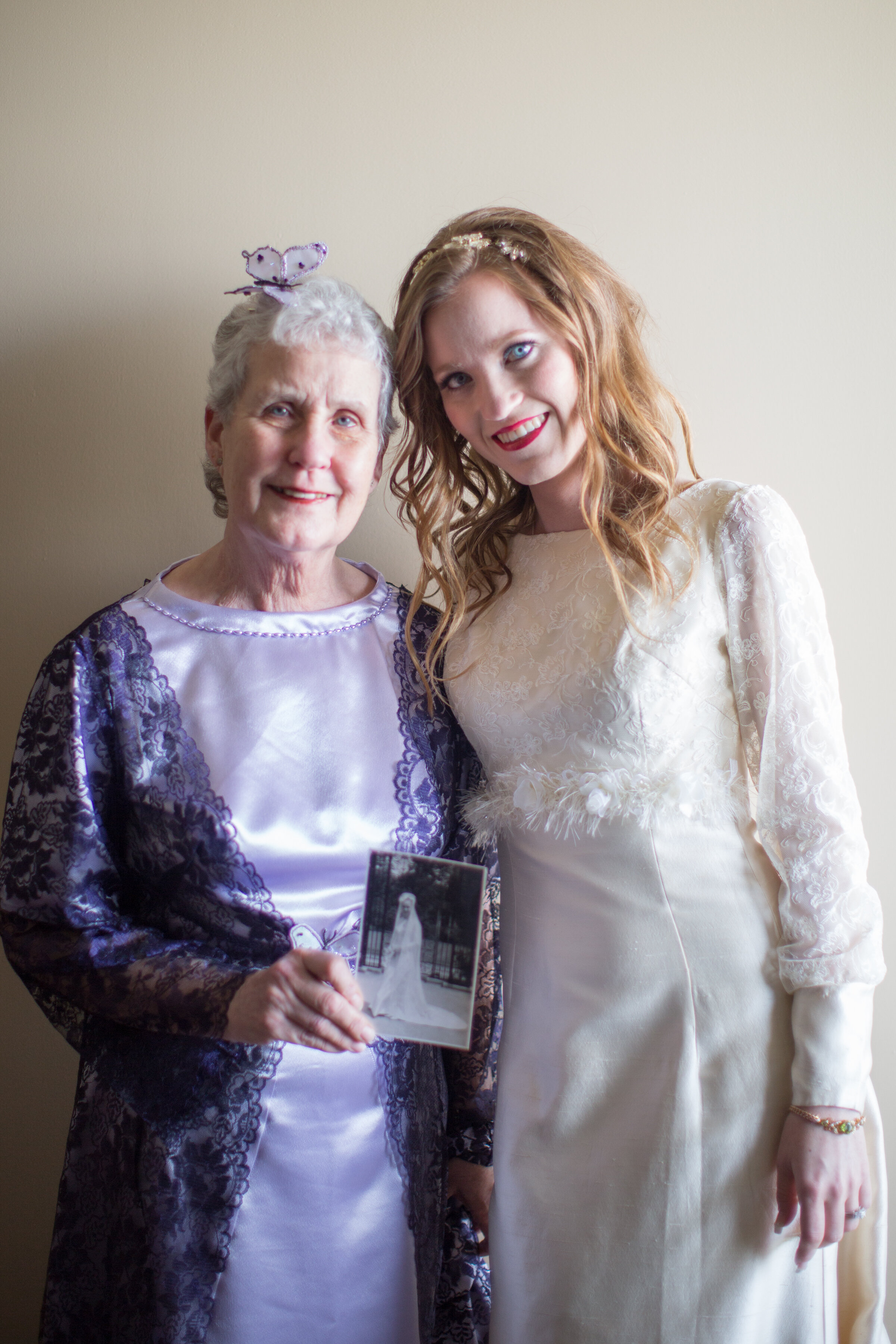 Grandmother and granddaughter showing redesigned grandmothers wedding dress with the picture of 1950s wedding.jpg