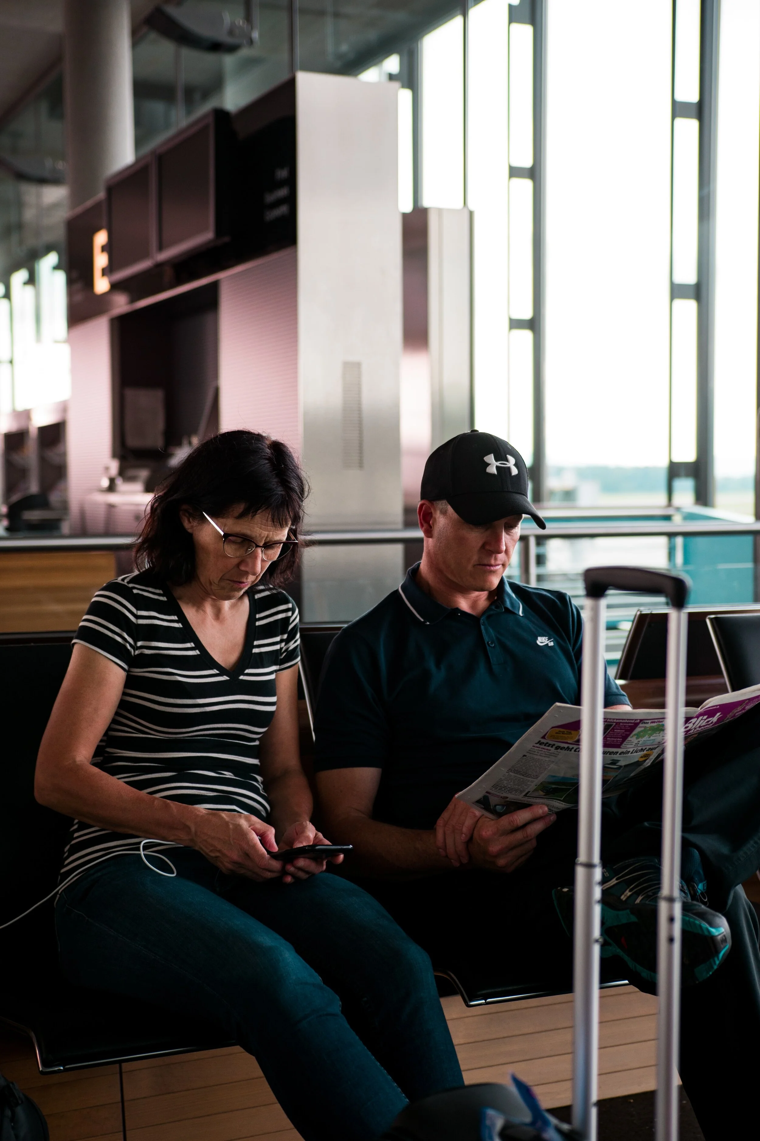 An older couple sitting in an airport reading.
