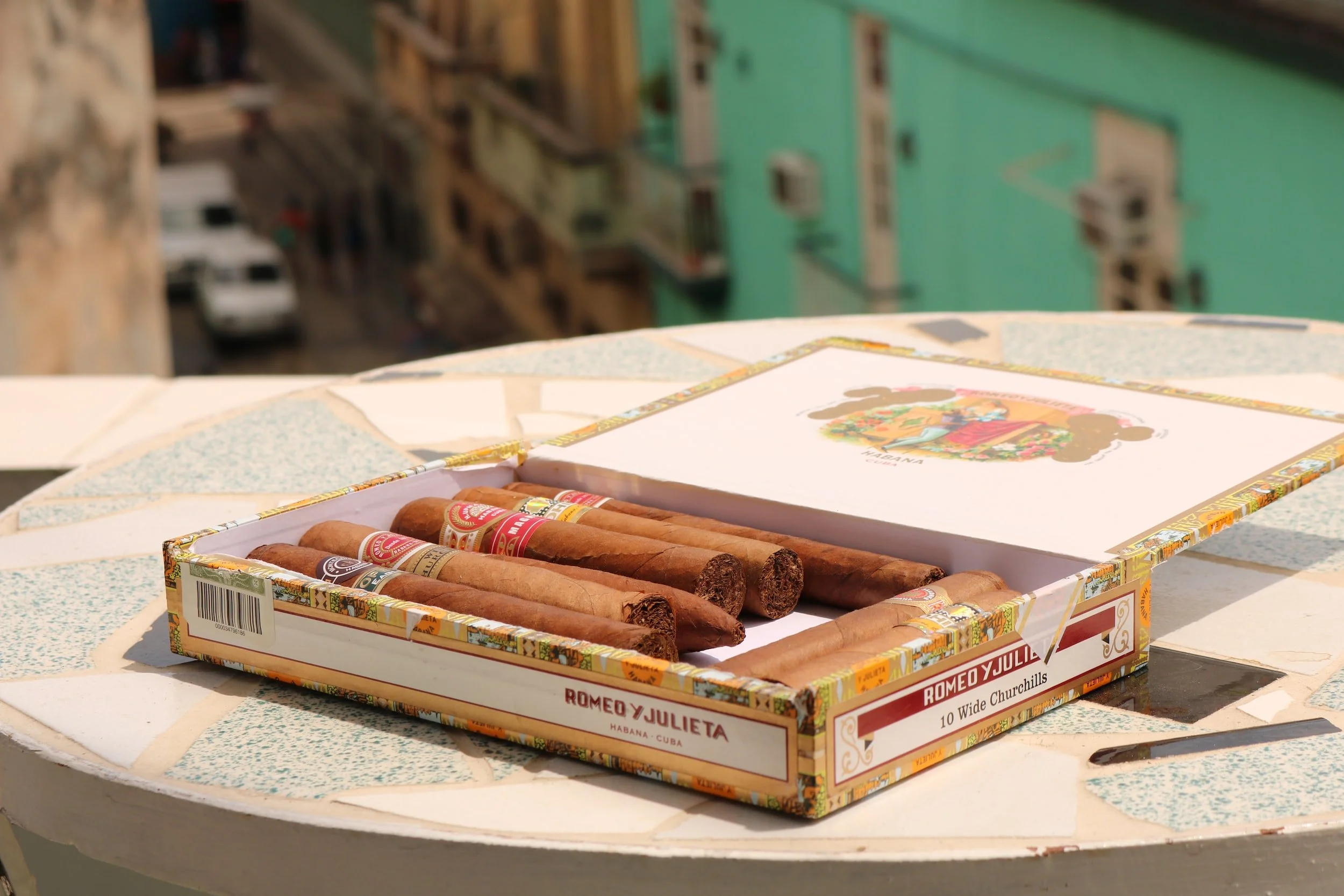 An open box of Cuban cigars on a table
