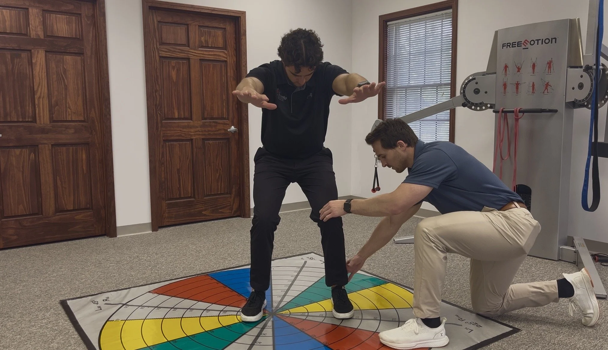 Sports chiropractor Dr. Brian Fuller assessing an athlete's squat technique and lower body biomechanics for sports injury rehabilitation at Indy Spine and Rehab.