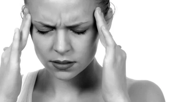 A person holding their temples from a severe migraine, representing headache treatment and cervicogenic relief at Indy Spine and Rehab in Carmel, Indiana.